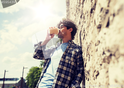 Image of man in eyeglasses drinking coffee over street wall