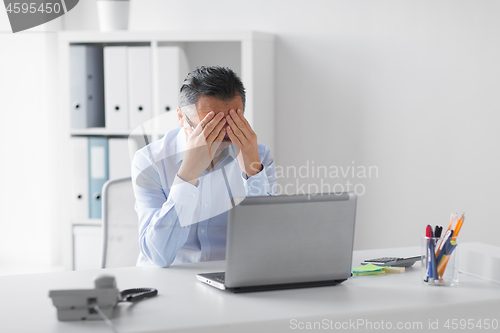 Image of stressed businessman with laptop working at office