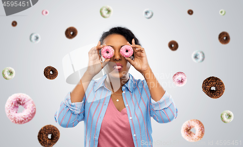 Image of happy african american woman with eyes of donuts