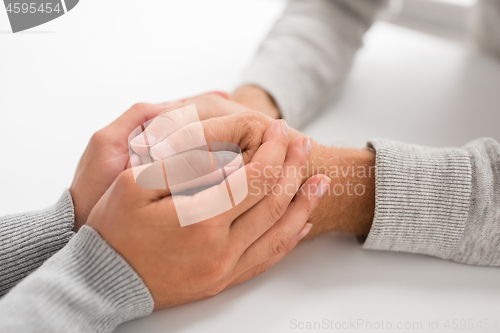 Image of close up of young woman holding senior man hands