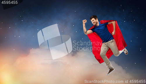 Image of man in red superhero cape flying over night sky