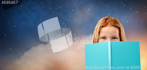 Image of red haired girl behind book over starry night sky