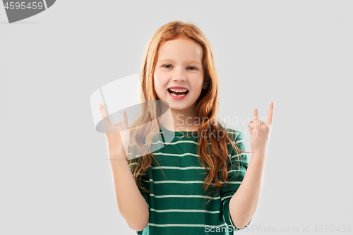 Image of smiling red haired girl showing rock gesture