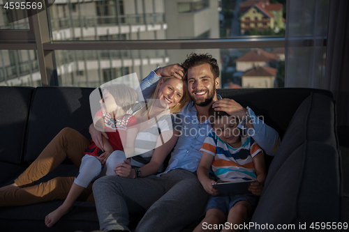 Image of happy young couple spending time with kids at home