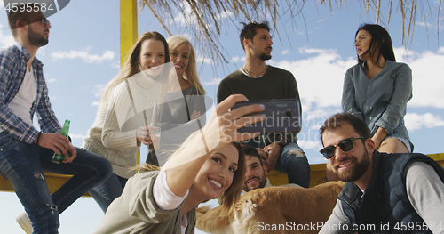 Image of Group of friends having fun on autumn day at beach