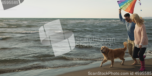 Image of couple with dog having fun on beach on autmun day