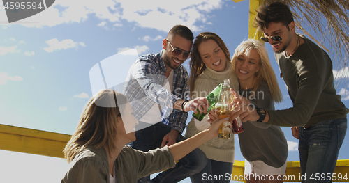 Image of Group of friends having fun on autumn day at beach