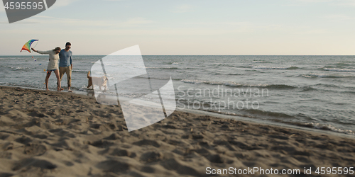 Image of couple with dog having fun on beach on autmun day