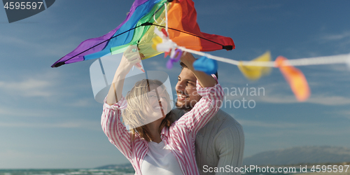 Image of Happy couple having fun with kite on beach