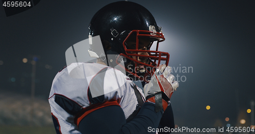 Image of American Football Player Putting On Helmet on large stadium with