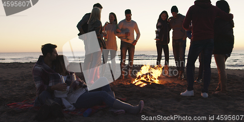 Image of Friends having fun at beach on autumn day