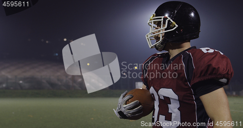 Image of American football player holding ball while running on field