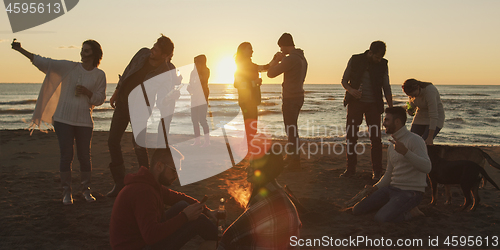 Image of Friends having fun at beach on autumn day