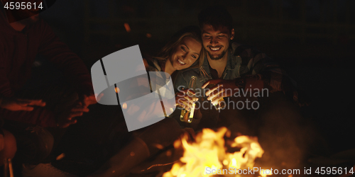 Image of Couple enjoying with friends at night on the beach