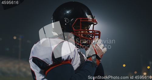 Image of American Football Player Putting On Helmet on large stadium with