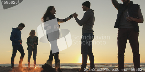 Image of Friends having fun at beach on autumn day