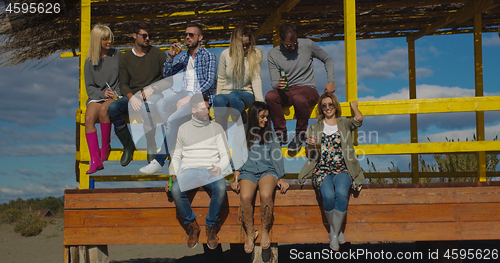 Image of Group of friends having fun on autumn day at beach