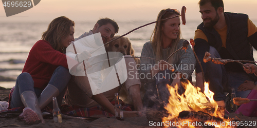 Image of Group Of Young Friends Sitting By The Fire at beach