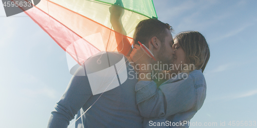 Image of Happy couple having fun with kite on beach