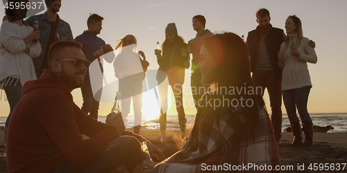 Image of Friends having fun at beach on autumn day