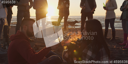 Image of Friends having fun at beach on autumn day