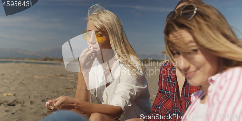 Image of Group of girlfriends having fun on beach during autumn day