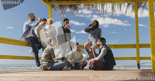 Image of Group of friends having fun on autumn day at beach