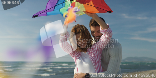 Image of Happy couple having fun with kite on beach