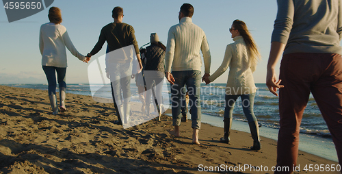 Image of Group of friends having fun on beach during autumn day