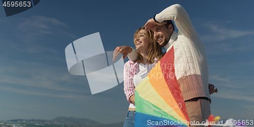 Image of Happy couple having fun with kite on beach