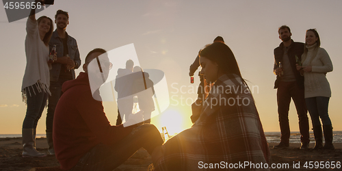 Image of Friends having fun at beach on autumn day