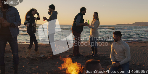 Image of Friends having fun at beach on autumn day