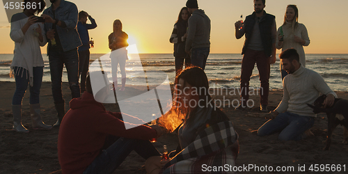 Image of Friends having fun at beach on autumn day