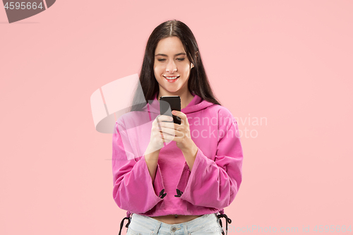 Image of Young beautiful woman using mobile phone studio on pink color background