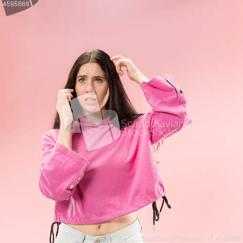 Image of Young beautiful woman using mobile phone studio on pink color background