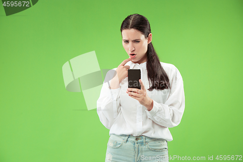 Image of Young beautiful woman using mobile phone studio on green color background