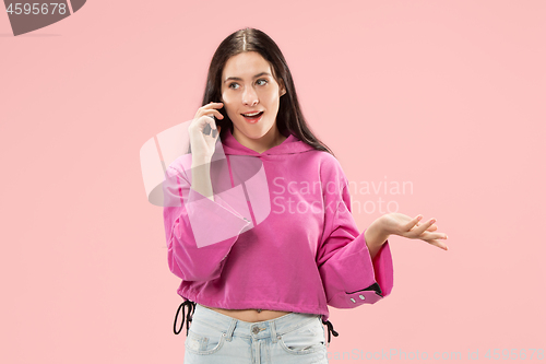 Image of Young beautiful woman using mobile phone studio on pink color background