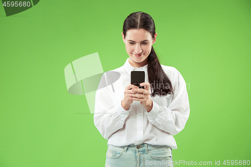 Image of Young beautiful woman using mobile phone studio on green color background