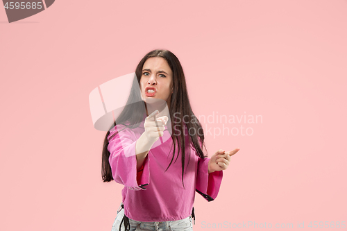 Image of Portrait of an angry woman looking at camera isolated on a pink background