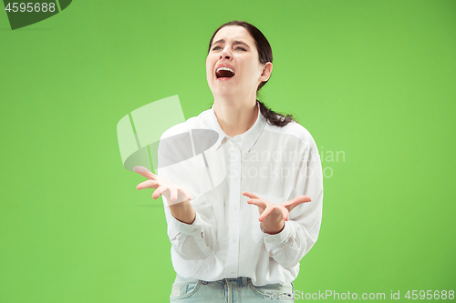 Image of Beautiful woman looking suprised and bewildered isolated on green