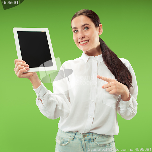 Image of Portrait of a confident casual girl showing blank screen of laptop isolated over green background