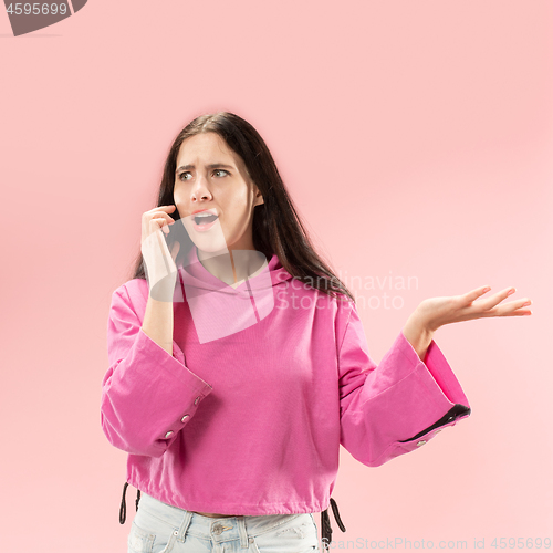 Image of Young beautiful woman using mobile phone studio on pink color background