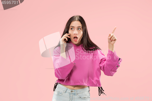 Image of Young beautiful woman using mobile phone studio on pink color background