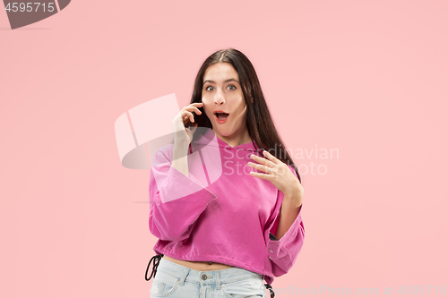 Image of Young beautiful woman using mobile phone studio on pink color background