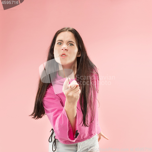 Image of Portrait of an angry woman looking at camera isolated on a pink background