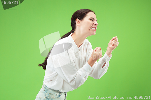 Image of Portrait of an angry woman looking at camera isolated on a green background