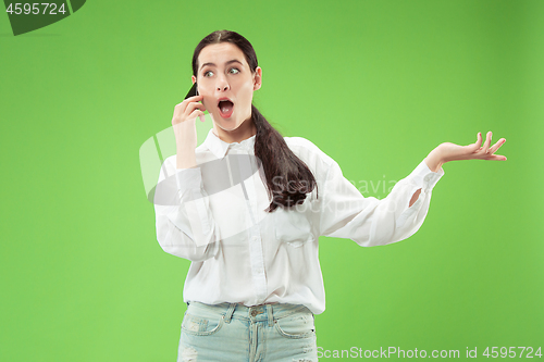Image of Young beautiful woman using mobile phone studio on green color background