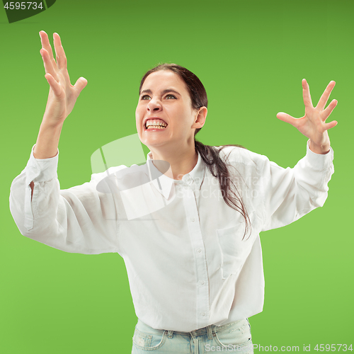 Image of Beautiful female half-length portrait isolated on green studio backgroud. The young emotional surprised woman