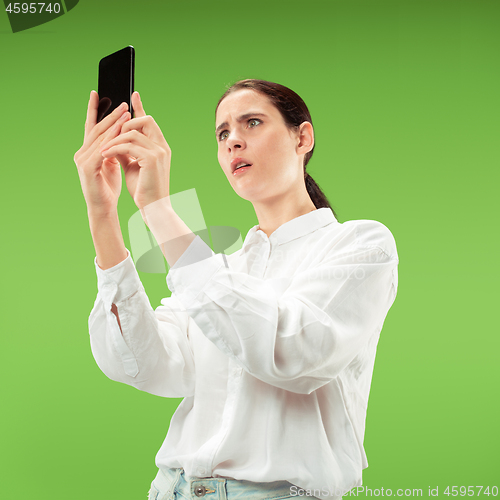 Image of Young beautiful woman using mobile phone studio on green color background