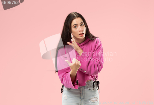 Image of The young woman whispering a secret behind her hand over pink background